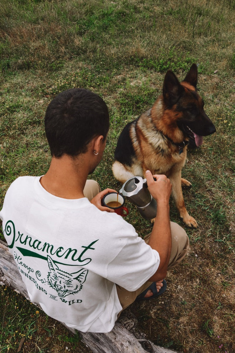 Hemp t-shirt with green coyote print on back on model with dog and coffee