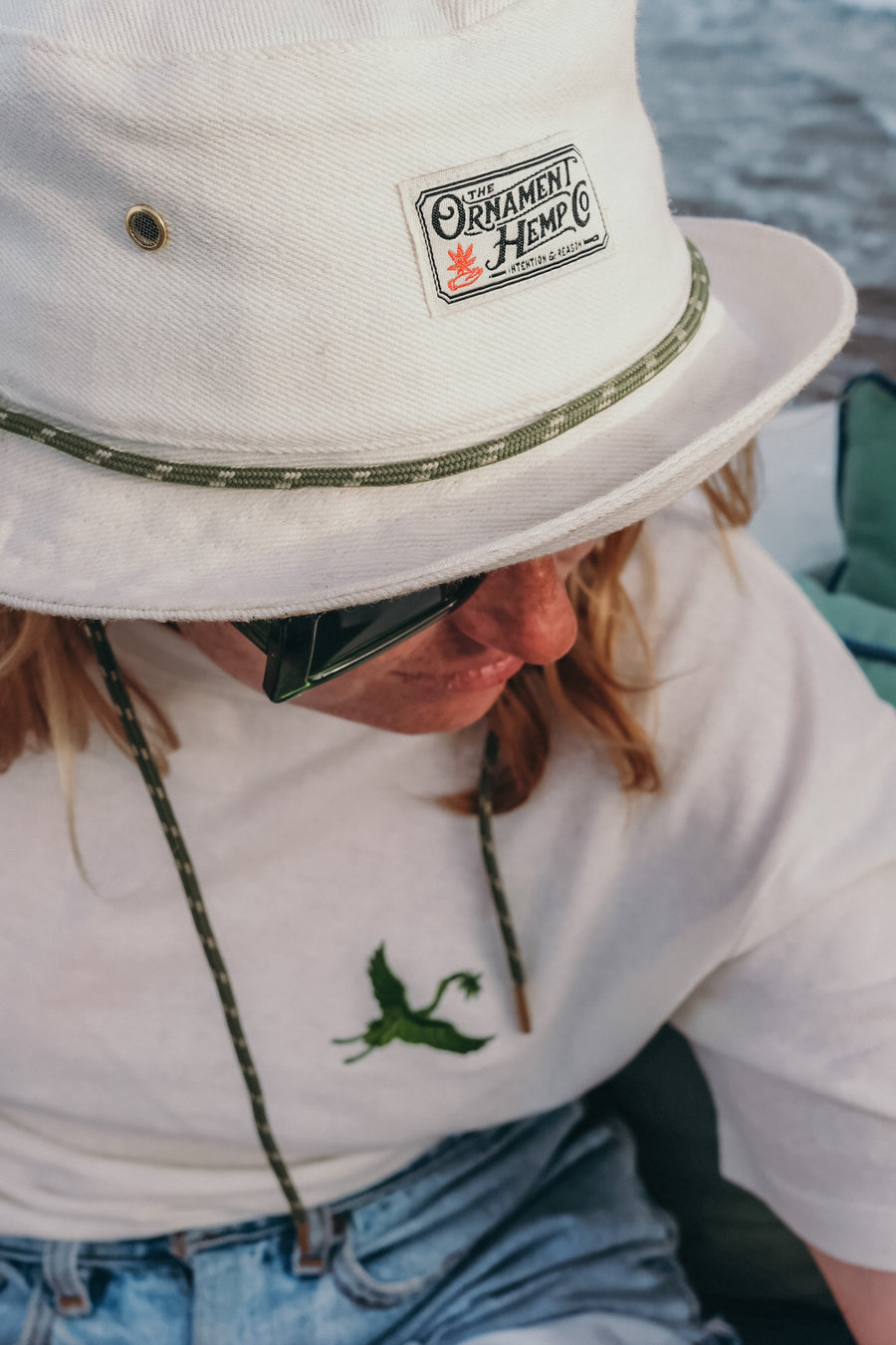 hemp bucket hat in off-white natural color with green string and metal ventilation holes on female